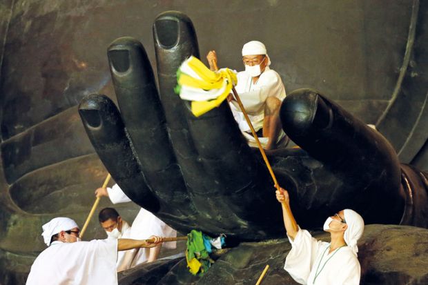 Buddhist monks clean dust off of the 15-meter-high Great Buddha's hand to illustrate Employment practices in Japan ‘turning off’ overseas scholars