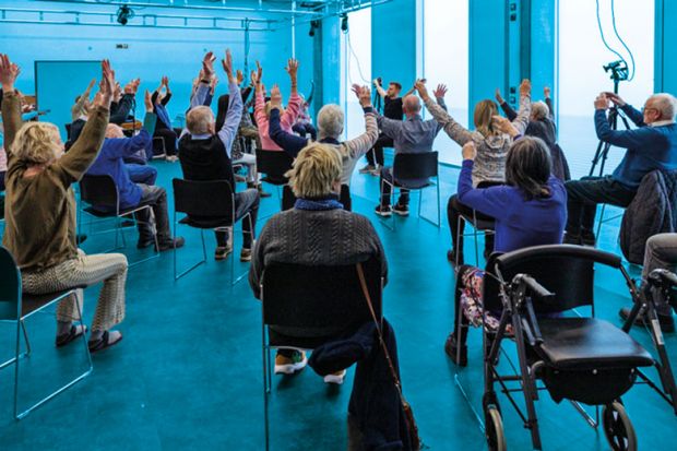 Group sitting with hands up doing exercises