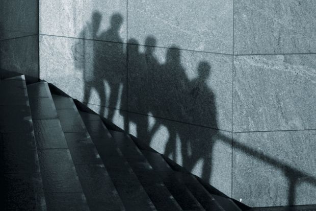 The shadows of anonymous people walking in one direction down stairs are seen on a wall in London as a metaphor for some students abusing privacy allowances