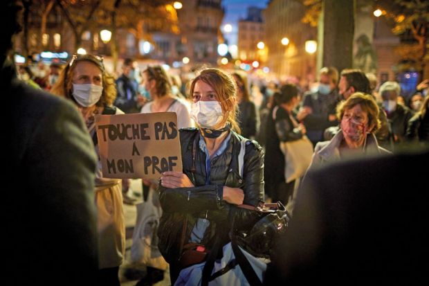  A member of the crowd watching the National Tribute to the murdered school teacher Samuel Paty holds a placard reading 'Do not touch my Professor' at Place de la Sorbonne on October 21, 2020 in Paris, France.