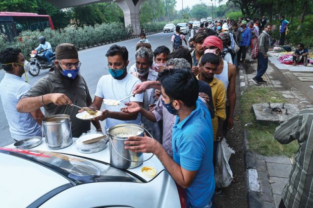 Homeless people queue for food along a road in New Delhi to show the hardship people have during Covid.