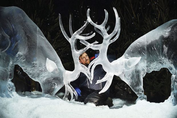 man looking at ice sculpture of two stags with horns together as a metaphor for ‘Nordic’ innovation vision for Scotland backs university mergers.