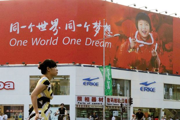 Person walking past a poster reading 'One World One Dream' in English and Chinese as a metaphor for Taiwan eyes international recruitment with switch to English.
