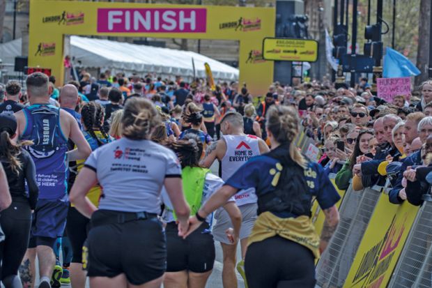 Runners holding hands approach the finish line at the London Landmarks Half Marathon 2024 to illustrate record numbers are getting clearing for university admissions