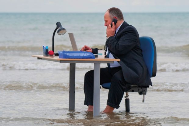 Businessman sitting at his office desk in the sea on Brighton beach to illustrate Labour’s ‘right to switch off’ is ‘unfeasible’ in UK academia