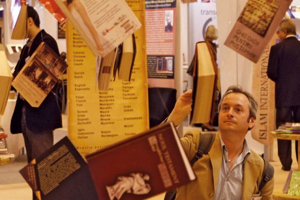 A man reads a book hanging at Earls Court Exhibition Centre in London to illustrate Dont wait to tackle open access books cash challenge, REF told