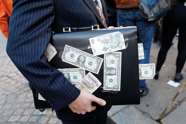 A protester dressed as a businessman, holds a briefcase covered in U.S. dollar notes to illustrate Stanford law school trials income-based student loans
