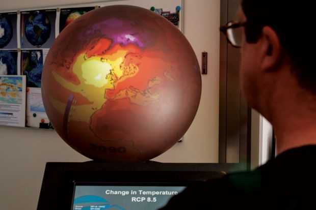 Person looking at screen next to supercomputer with red globe on top