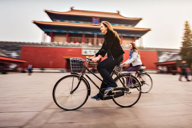 Friends riding retro bicycles along forbidden city