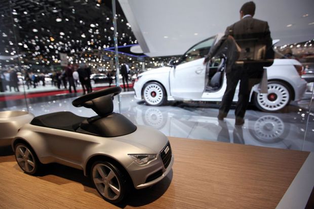 A toy car for Audi AG is seen on the company's stand with a man looking at white car in background