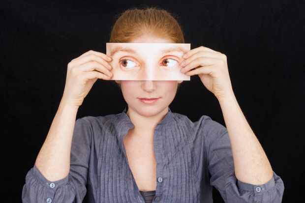 Woman holding print-out of eyes over face