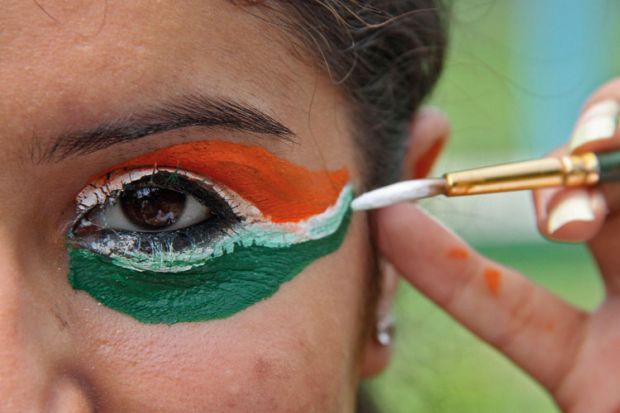 Woman painting eyes in colours of flag of India