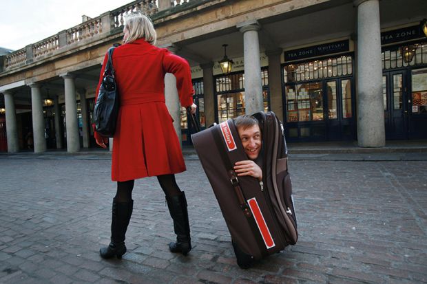 woman pulling along man hidden in suitcase