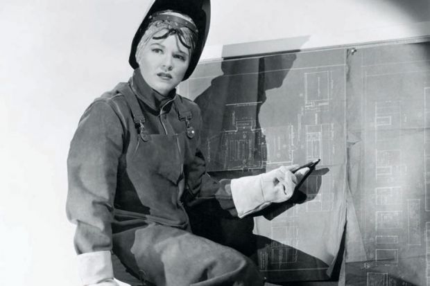 Woman wearing protective clothing pointing at blueprints
