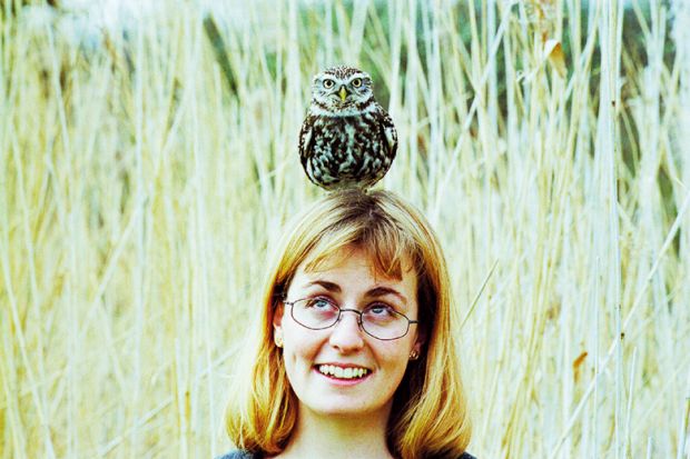 A woman with an owl balanced on her head