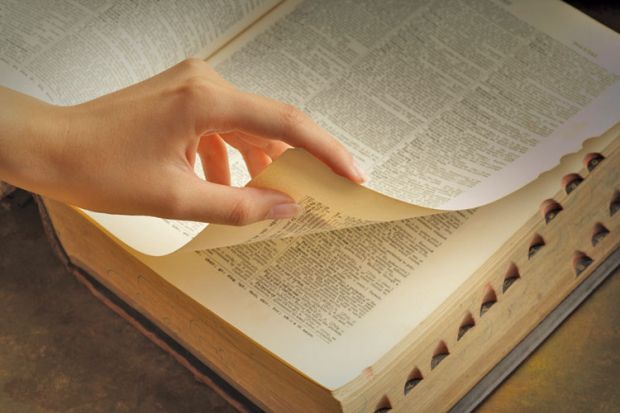Woman&#039;s hand turning dictionary pages