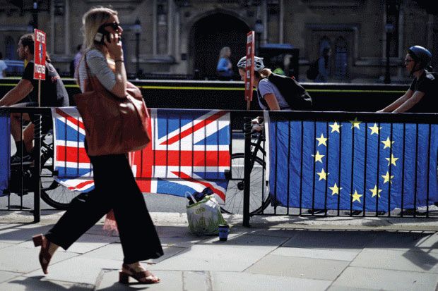 Woman walking past UK and EU flags