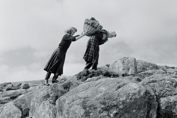 Women carrying basket up rocks