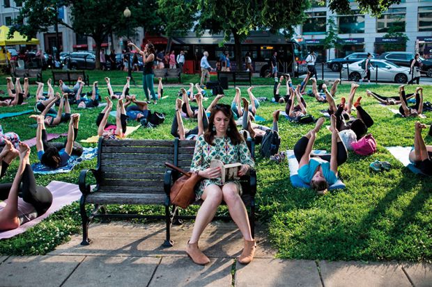 Woman on bench with outdoor yoga class behind her, illustrating lifelong learning