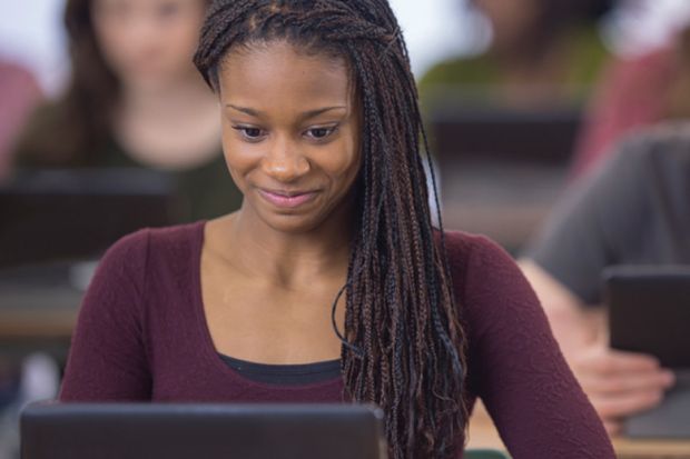 Young female student smiling and looking at computer monitor