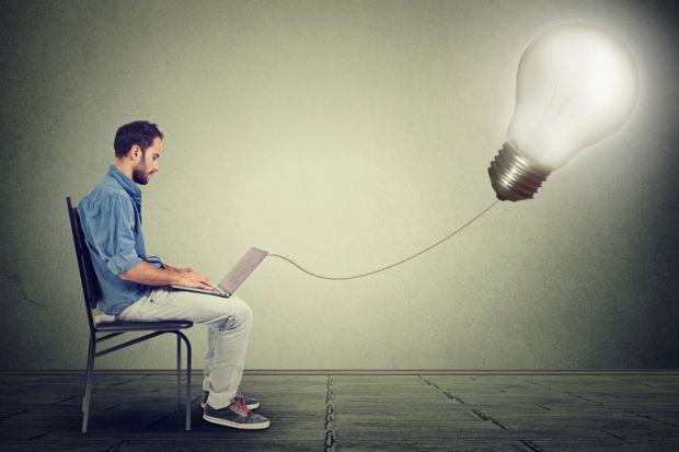 Young male entrepreneur using laptop, lightbulb, Eureka