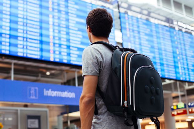Young man looking at airport departures board