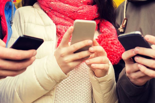 Young people gathered together using smartphones