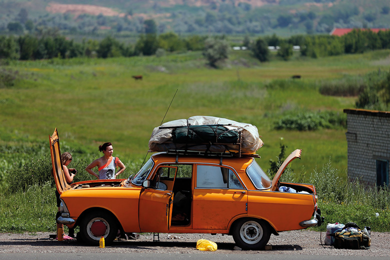 Women repair orange car, Donetsk, Ukraine